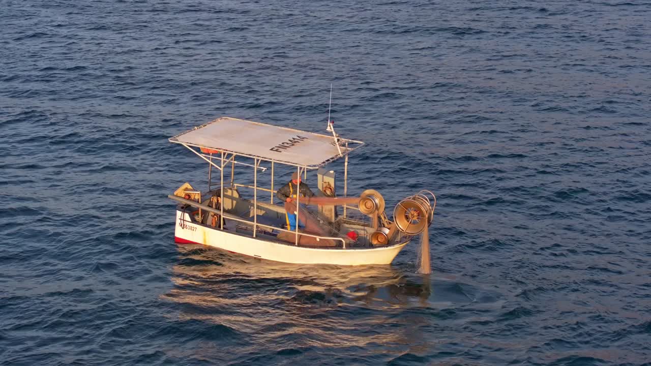 Vista aerea di una barca solitaria che recupera le reti da pesca all'alba, Costa Azzurra, Francia