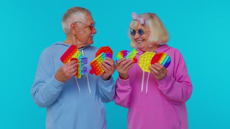 sonriente anciano abuela abuelo sosteniendo anti-estrés pantalla táctil empuje pop es un juguete popular