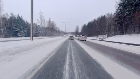 cars driving on a highway in a snow covered winter landscape