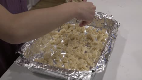 a young girl prepares the crust in a baking tray for making millionaire shortbread cookies-1