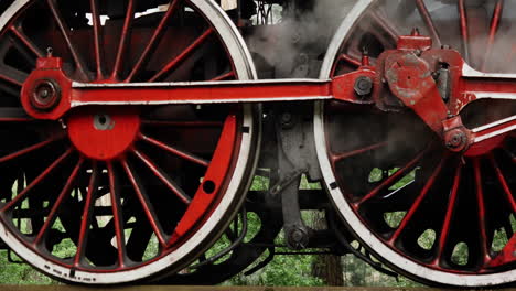 primer plano de las ruedas de acero del tren de vapor alimentado por carbón que se detiene con humo de vapor blanco