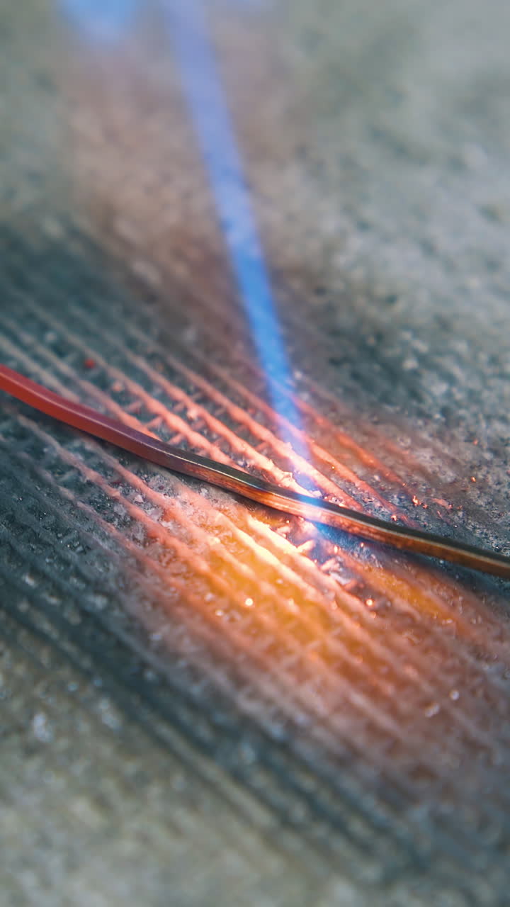 CU: heating of thin gold metal wire with gas burner on fireproof asbestos sheet in handicraft jewelry workshop closeup