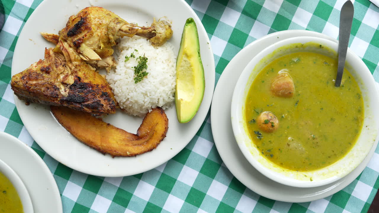 Descubre los ricos sabores del sancocho de gallina colombiano servido con arroz y aguacate. Capturado en el Valle del Cauca con luz natural vibrante, realzando la apetitosa gastronomía.