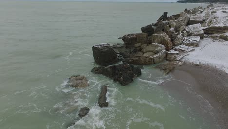 aerial birdseye view of abandoned seaside fortification buildings at karosta northern forts on the beach of baltic sea , overcast winter day, distant wide orbiting drone shot