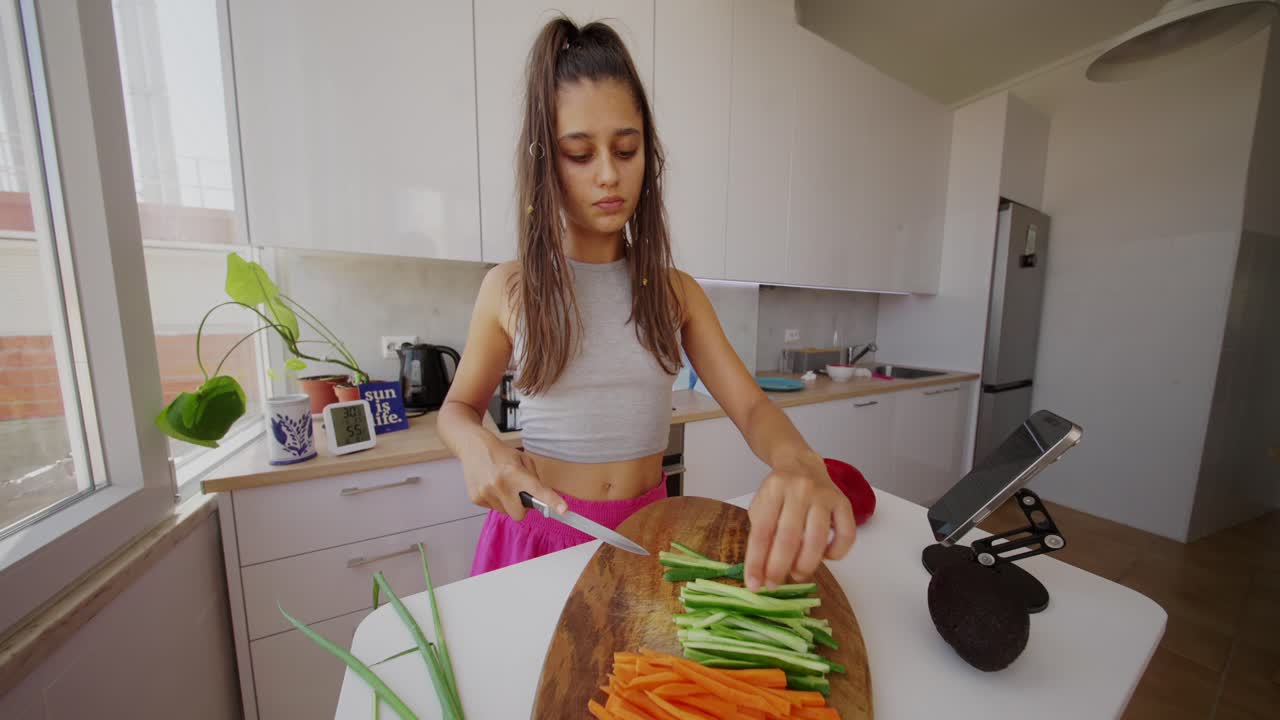 Mujer joven cortando verduras en una cocina luminosa