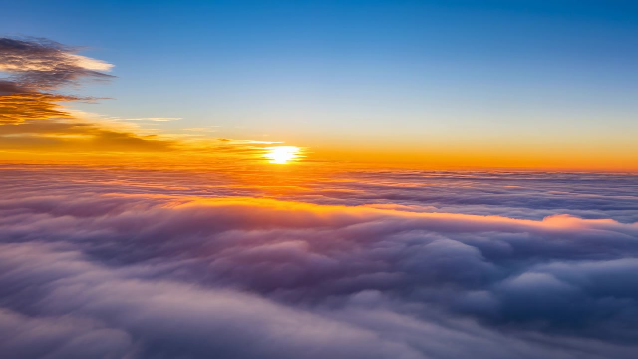 Alba sopra le nuvole che inonda l'orizzonte di luce dorata, prospettiva aerea di un manto di nuvole infinito e morbido.