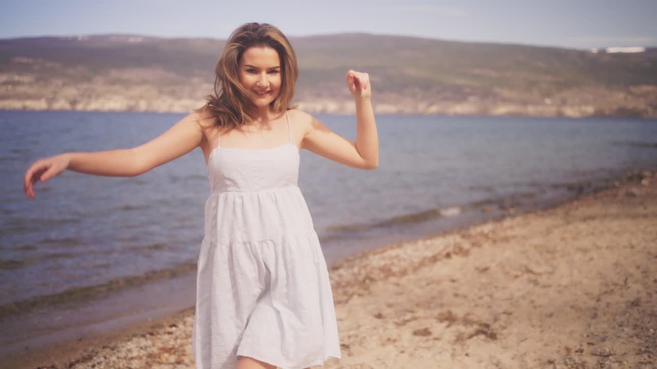 Playful girl in a white dress on a beach