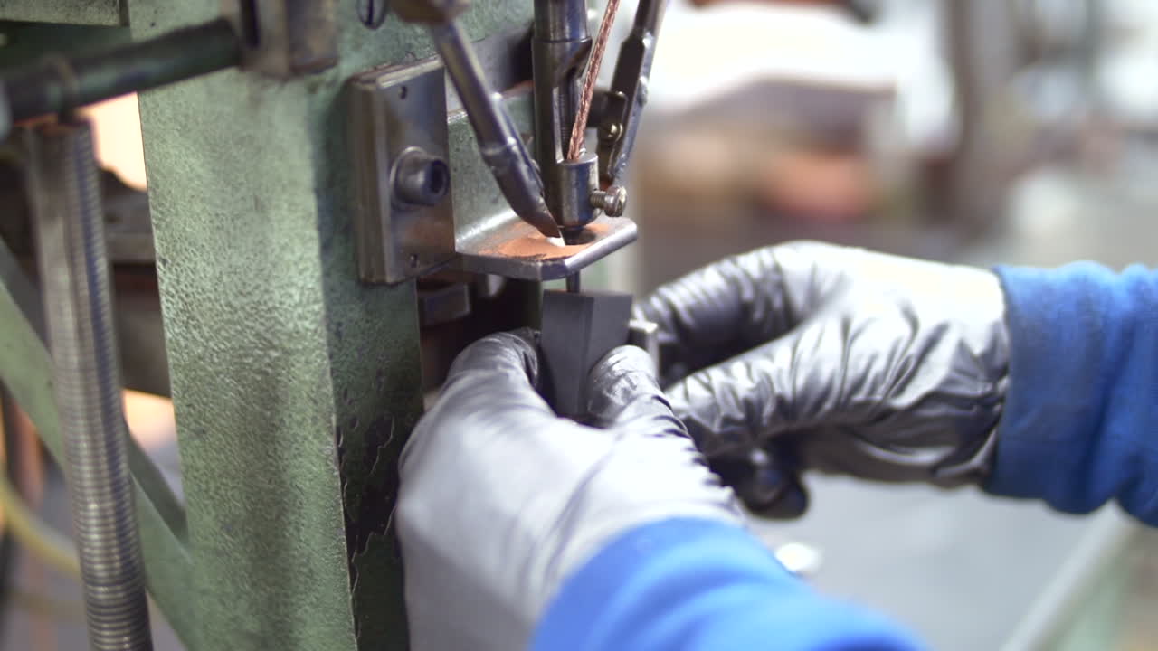 A worker using a machine to drill into a metal piece