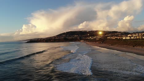 un dron vuela hacia un cielo increíble mientras las olas chocan en la costa de la playa