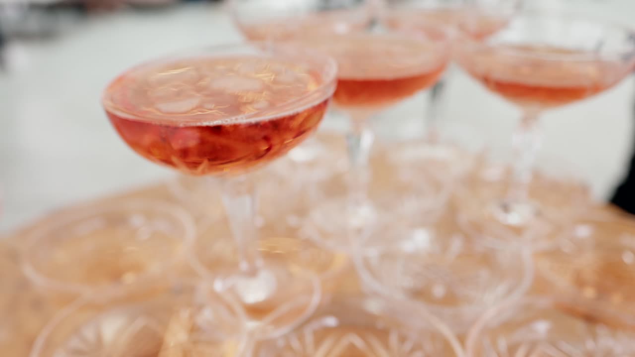 close up of filled coupe glasses forming a rosé champagne tower for festive celebration