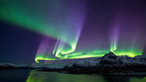 aurora borealis over snowy mountains and water