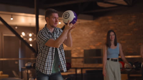 Portrait-A-young-man-makes-the-final-throw-with-a-bowling-ball-and-wins-the-game-with-the-support-and-joy-of-his-friends-of-different-nationalities.-Rejoice-and-celebrate-the-victory