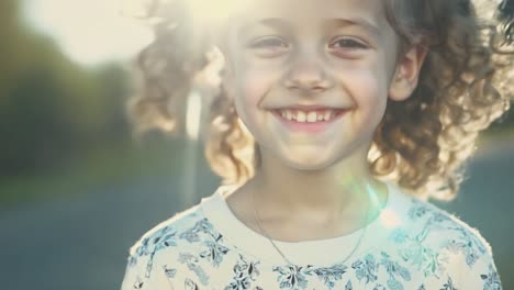 a young girl with curly hair smiling outdoors