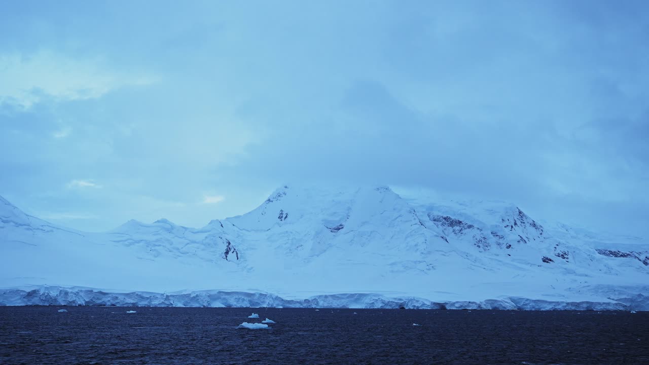 Winter Mountains Coastal Scenery in Antarctica, Cold Blue Landscape with Glacier Ice and Ocean Sea Water on Coast, Antarctic Peninsula Seascape in Dramatic Moody Blue Atmospheric Scene