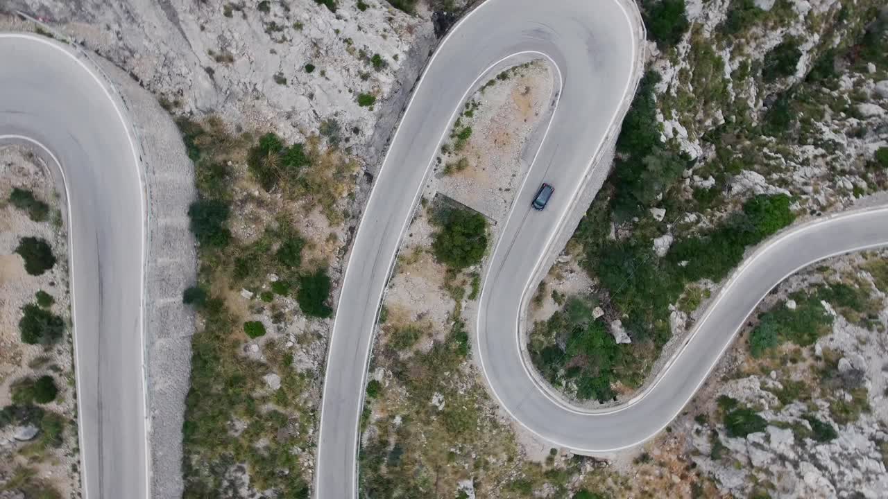 impresionante vista de arriba hacia abajo de 4k de un automóvil que conduce a través de serpentinas muy curvas - mallorca sa calobra serra de tramuntana - calle de montaña con curvas y peligrosas - conducción en carretera de montaña