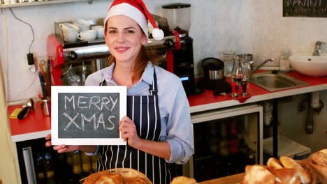 Portrait-of-waitress-showing-chalkboard-with-merry-x-mas-sign