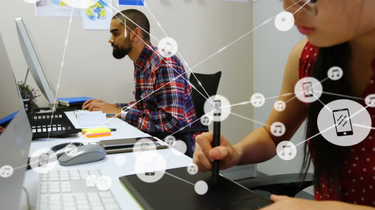 animación de una red de iconos digitales contra una mujer asiática que usa una tableta gráfica en la oficina