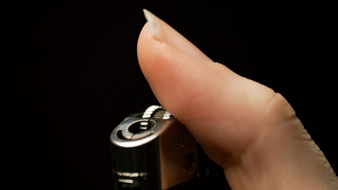 chispa a cámara lenta: observa cómo una mano enciende un encendedor, el pulgar lo activa en una hipnotizante exhibición de chispas y llamas en cámara lenta