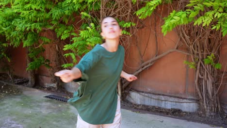 A woman dancing outdoors in a green t-shirt and khaki pants