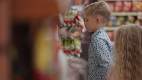 una niña va al refrigerador en un supermercado con una máscara protectora. compra productos con una máscara