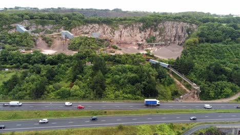 aerial rising above north wales expressway to cemex mining development site on lush greenery hillside