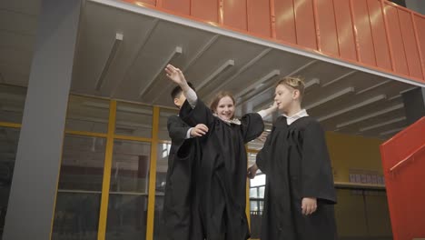 happy multiracial students throwing their mortarboards up in the air. they hug.