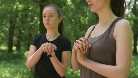 two happy pretty female runners warming up and streching their wrists in the park