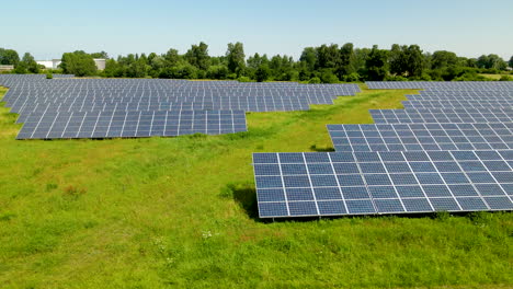 Solar-panel-farm-with-green-grass-on-sunny-day-in-Poland,-aerial