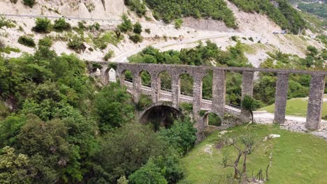 Drone-footage-of-the-historic-Aqueduct-of-Ali-Pasha-in-Bënçë,-Albania,-showcasing-its-impressive-stone-arches-and-scenic-surroundings