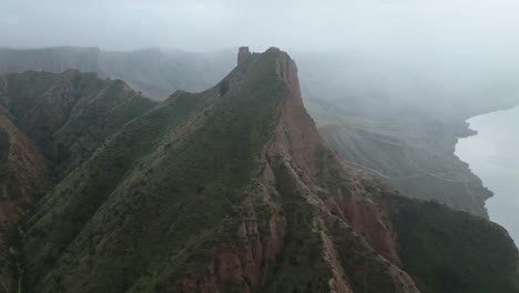 Mountain-ridge-near-river-on-foggy-day