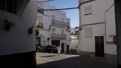 girl in white dress walking through empty street of olvera, spain