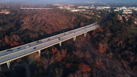 aerial fly over the top of a bridge panning to a suburban city at sunset