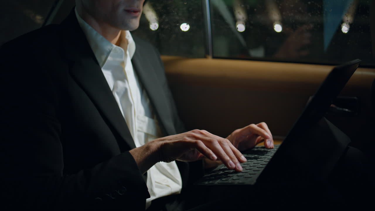 차에서 컴퓨터 키보드를 입력하는 사업가 손. 긴장한 사람이 일하고 있습니다.