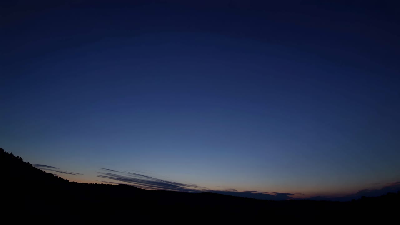 Wide-angle shot of a serene twilight sky over a silhouette landscape, capturing the peaceful