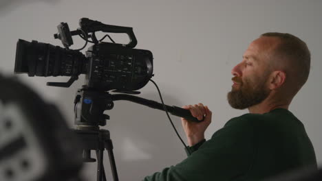 close up of male film camera operator focusing lens on camera shooting movie or video in studio 4