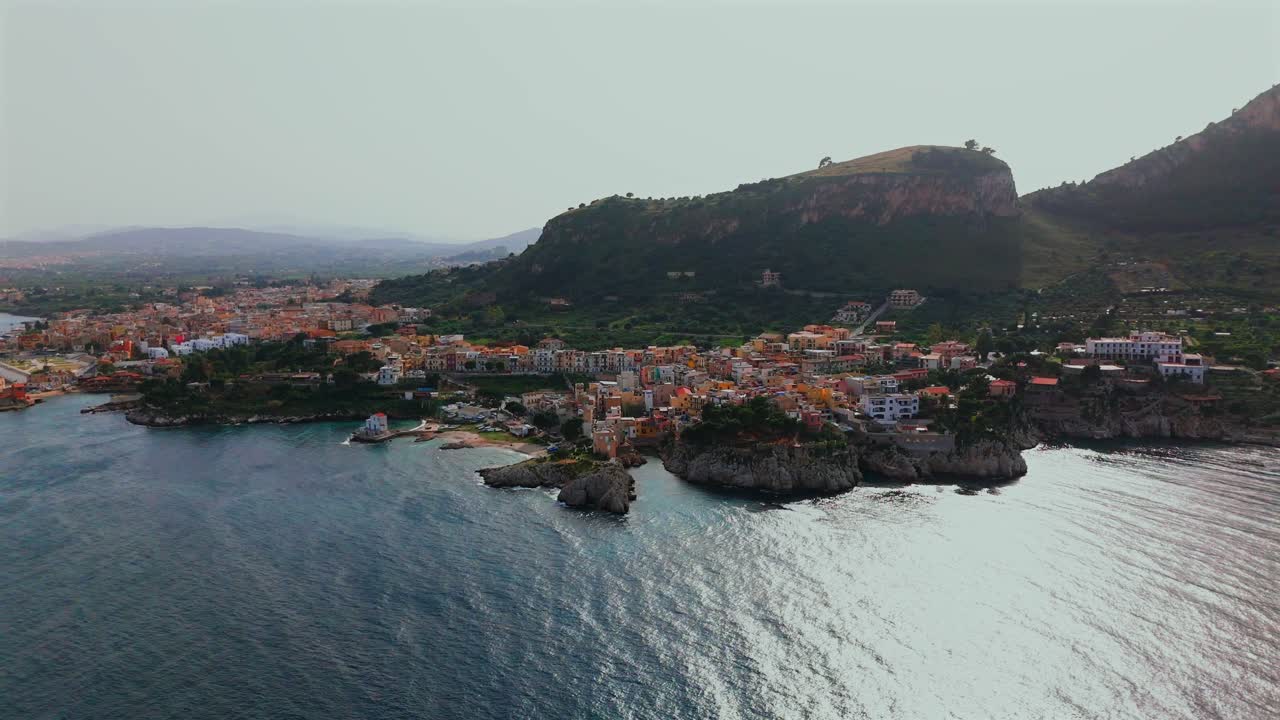 Slow motion 4K drone footage of Porticello Sicily showing full coastline lighthouse cliffside homes Monte Catalfano and colorful village buildings along the Tyrrhenian Sea in soft daylight