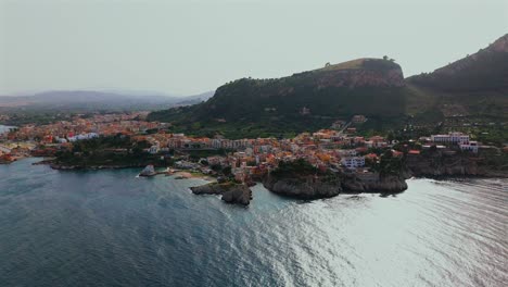 slow motion 4k drone footage of porticello sicily showing full coastline lighthouse cliffside homes monte catalfano and colorful village buildings along the tyrrhenian sea in soft daylight