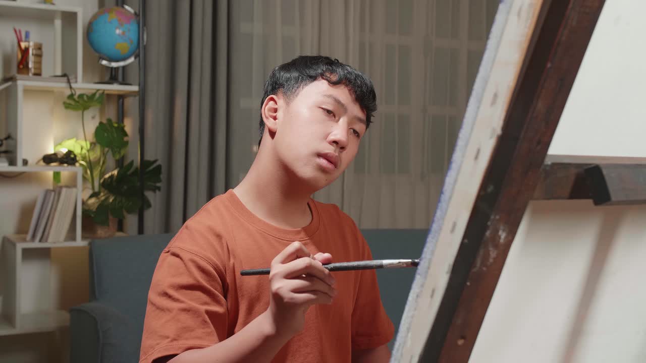 Medium Close Up Of An Asian Artist Boy Holding Paintbrush Mixed Colour And Thinking Before Painting On The Canvas
