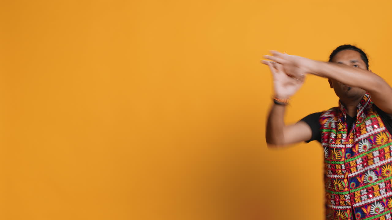 Lively man doing entertaining bollywood dance choreography, studio background