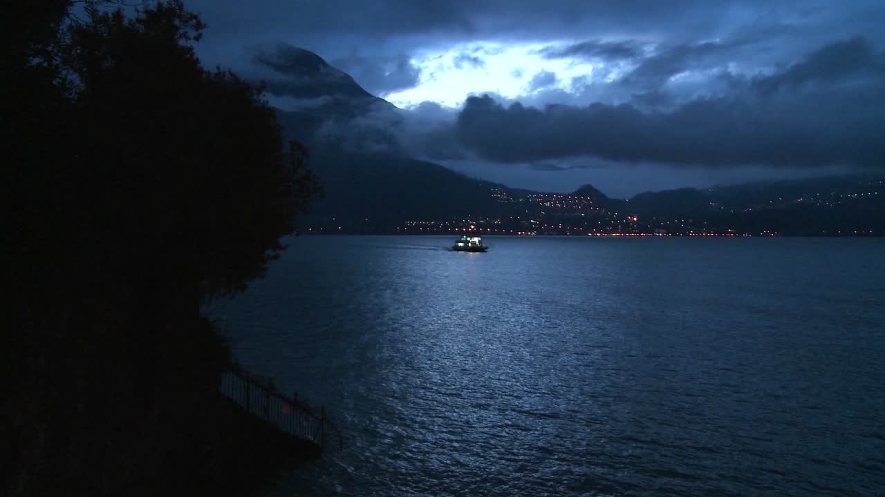 Gece karanlık bir gölde karşıya geçen uzaktaki bir tekne