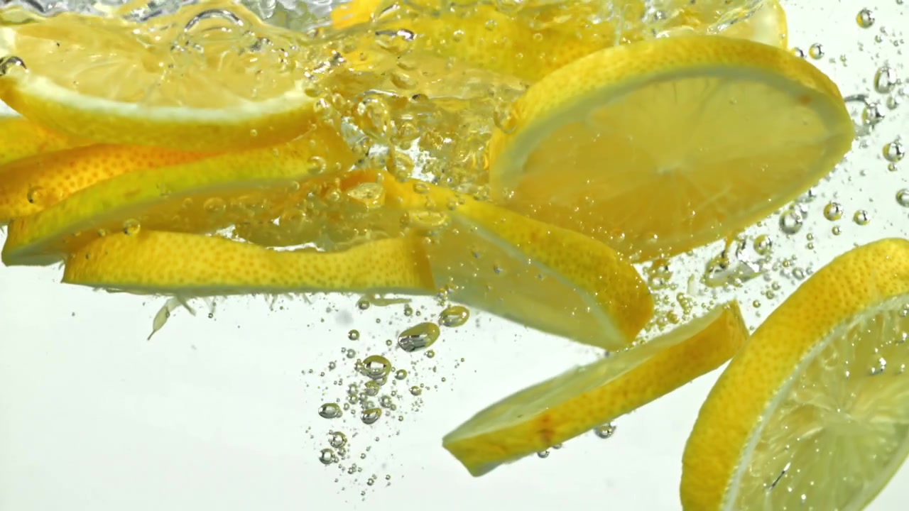 Slow Motion of Yellow Lemon Slices Falling into Water with Bubbles
