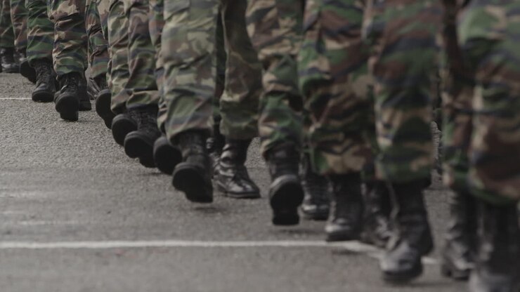 Molti uomini in marcia con stivali e abbigliamento militare