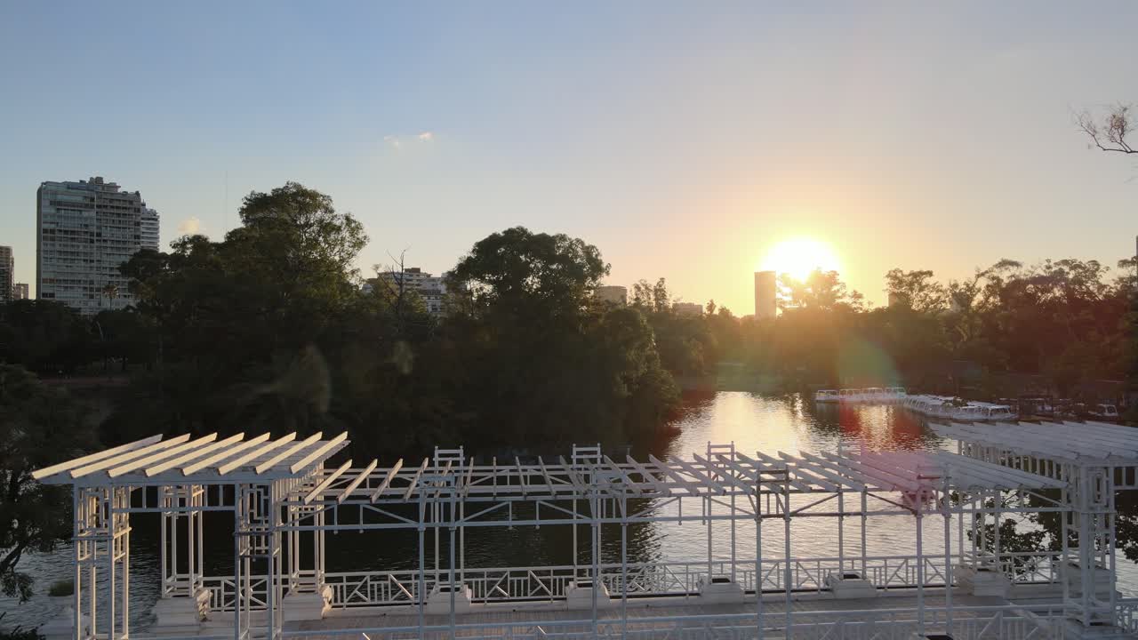 dolly aéreo fuera de los barcos que navegan bajo el puente blanco en el estanque de rosedal gardens a la hora dorada, buenos aires