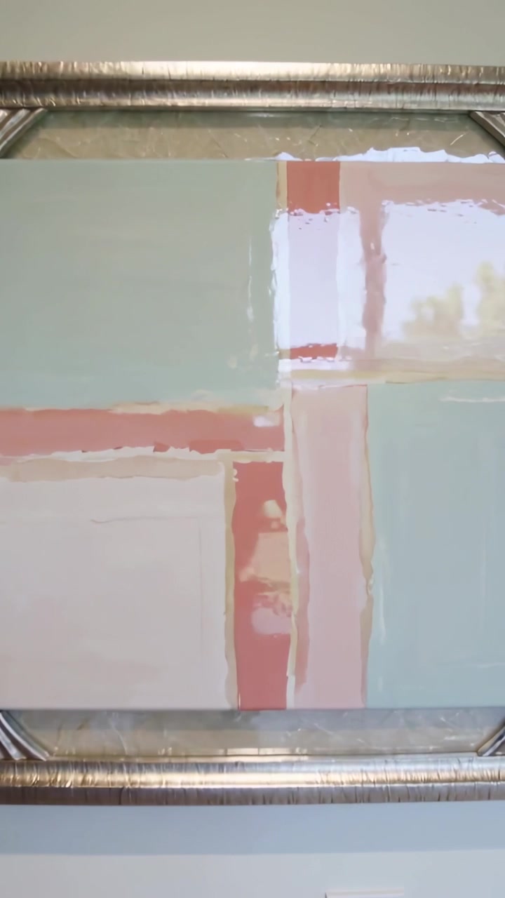 Vertical video: Panning camera revealing silver-framed painting on wall, showing window reflection