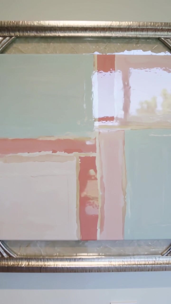 Video verticale: Panoramica della telecamera che rivela un quadro con cornice argentata su una parete, mostrando il riflesso di una finestra.