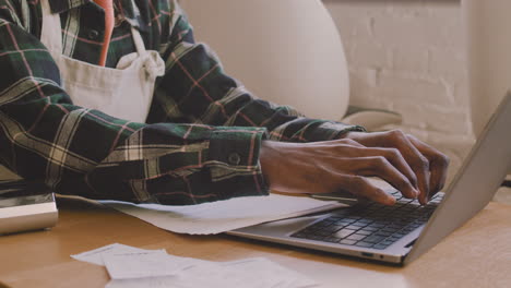 coffee shop owner sitting at table and calculating finance bill on laptop computer 1