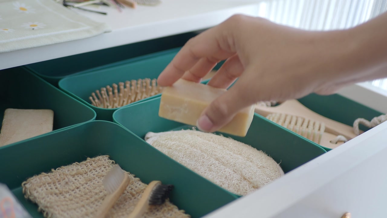 Hand Picking Up Bar Soap from Organized Eco-Friendly Bathroom Drawer