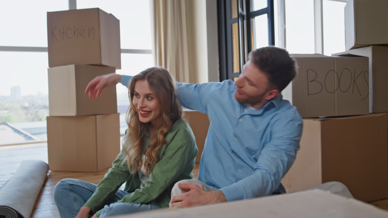 New homeowners sitting tired of moving in purchased house. Property owners rest