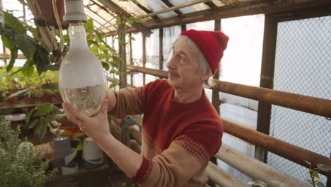elderly man replacing lightbulb in greenhouse farm