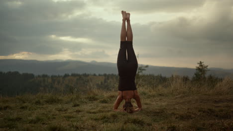 mujer atlética haciendo postura de yoga de pie en la cabeza. chica de fitness de pie en la cabeza al aire libre